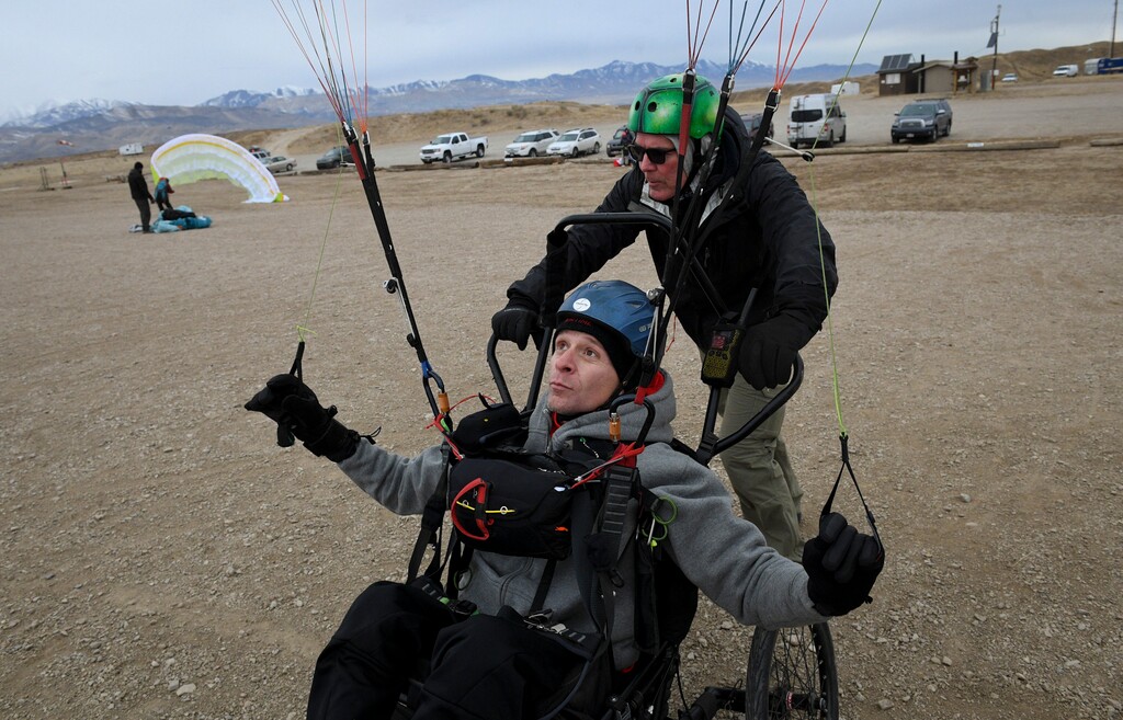 (Isaac Hale | The Daily Herald | The Associated Press) In this Saturday, Jan. 6, 2018 photo, Sam Jolley practices ground handling and other paragliding skills with the help of Mark Rich, a Draper resident with Project Airtime, before taking flight at the Flight Park State Recreation Area in Draper, Utah. Jolley, who was left paralyzed after an accident, learned how to paraglide with Project Airtime, a Draper-based non-profit that aims to get everyone into the skies.