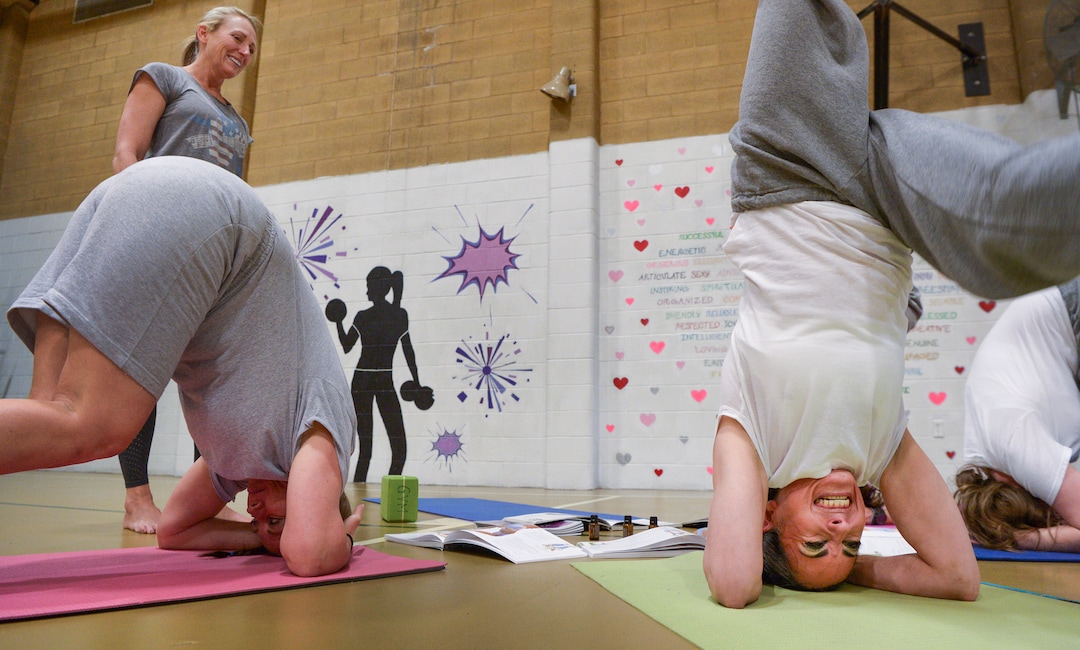 Leah Hogsten  |  The Salt Lake Tribune  l-r Denise Druce, left, started volunteering at Timpanogos WomenÕs Correctional Facility in December 2017, but she wanted to do more than just teach yoga classes. She wanted to teach the women how to lead their own groups. Druce smiles as Ferosa Bluff, right, and fellow yoga apprentices grimace and groan trying to get into a yoga pose. Every Friday, the Timpanogos Women's Correctional Facility gymnasium at the Utah State Prison is filled with a joyful silence as inmates practice yoga.