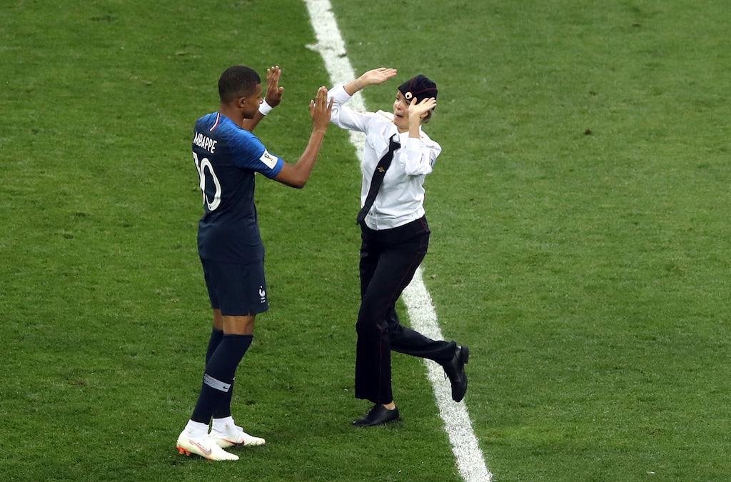 A woman who invaded the pitch approaches France's Kylian Mbappe during the final match between France and Croatia at the 2018 soccer World Cup in the Luzhniki Stadium in Moscow, Russia, Sunday, July 15, 2018. (AP Photo/Thanassis Stavrakis)