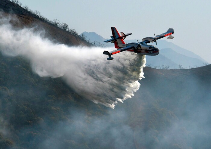 (Mike Eliason | Santa Barbara County Fire Department via AP) In this photo provided by the Santa Barbara County Fire Department, a Bombardier 415 Super Scooper makes a water drop on hot spots along the hillside east of Gibraltar Road in Santa Barbara, Calif., Sunday morning, Dec. 17, 2017. One of the largest wildfires in California history is now 40 percent contained but flames still threaten coastal communities as dry, gusty winds are predicted to continue.