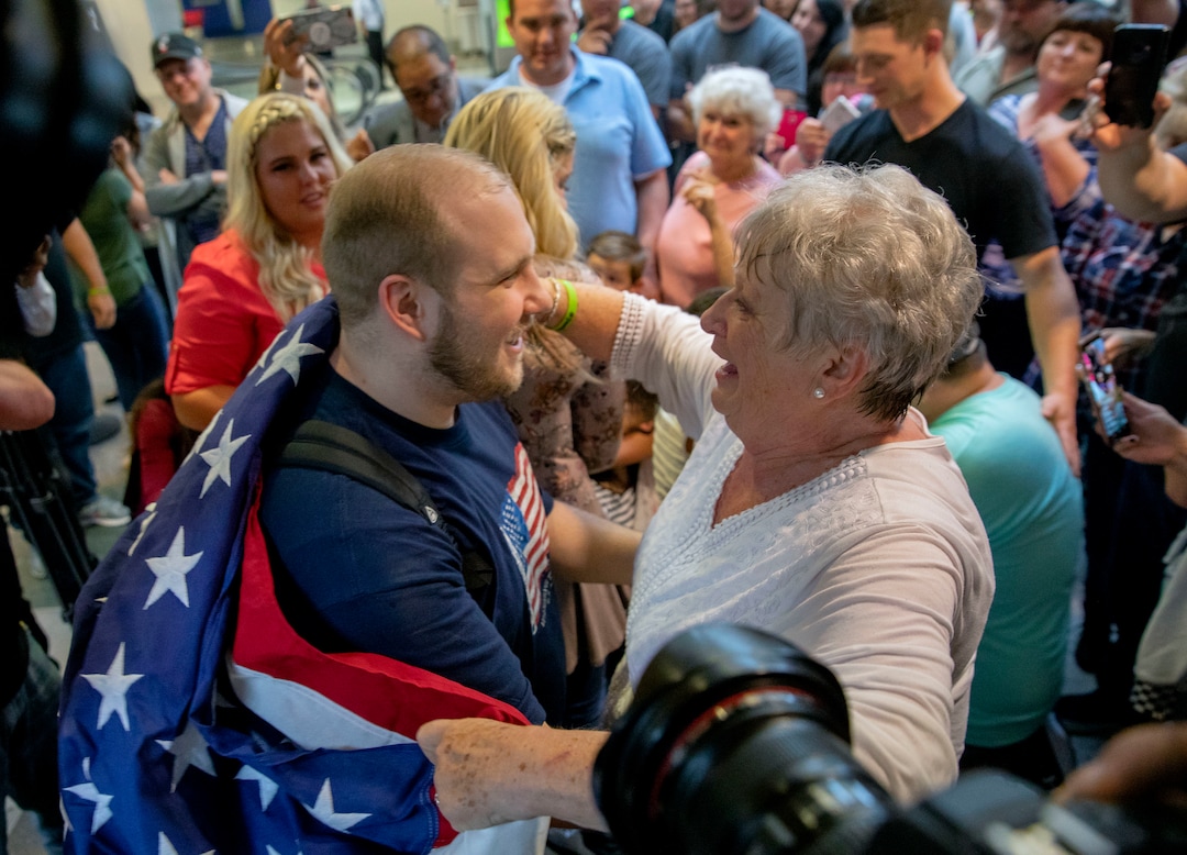 Josh Holt, left, is draped in an America flag by his grandmother, Linda Holt, upon returning to Salt Lake City on Monday, May 28, 2018, as he was freed this weekend after being held in a Venezuelan jail for nearly two years. He returned home to Salt Lake City on Monday night after getting medical care and visiting President Donald Trump in Washington. (AP Photo/Kim Raff)