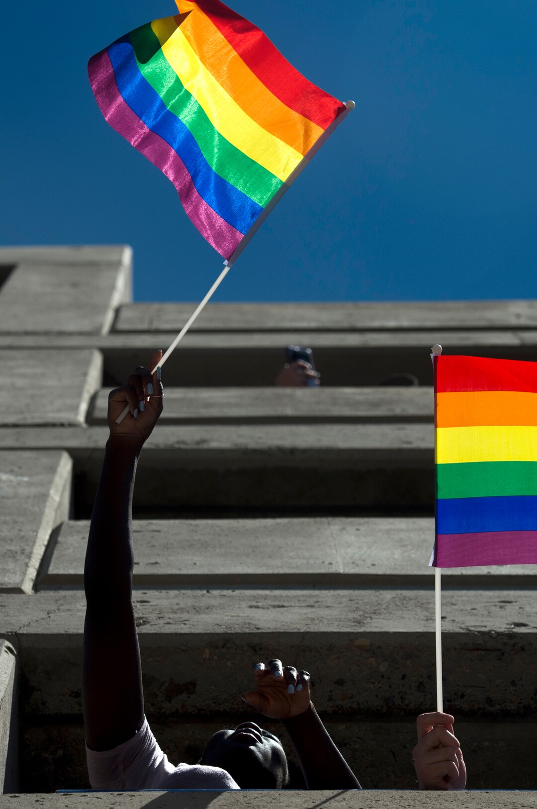 (Rick Egan  |  The Salt Lake Tribune)   Mixsa Kafi waves a rainbow flag as she watched the Utah Pride Parade from a parking terrace, Sunday, June 3, 2018.
