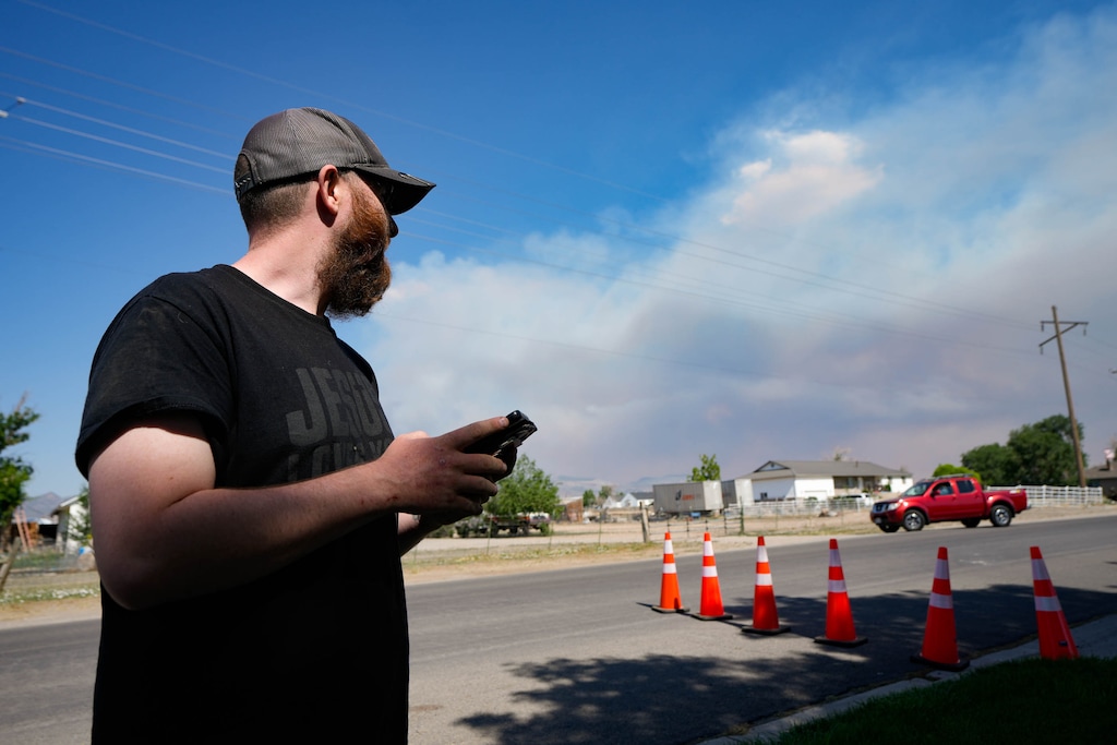(Francisco Kjolseth | The Salt Lake Tribune) Eureka resident Daniel Rosenbaum checks for updates on the Iron Fire burning in the distance while sheltering in the nearby town of Elberta on Monday, June 22, 2026. 