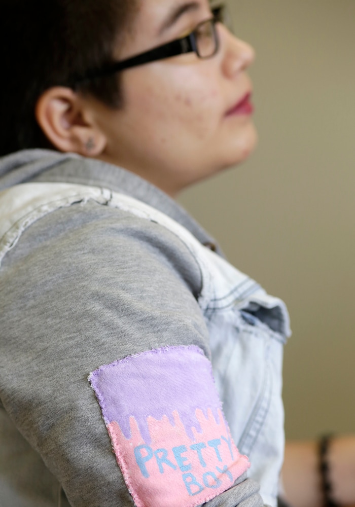 (Lynne Sladky | The Associated Press) In this Thursday, Oct. 8, 2015 photo, Theo Ramos, 14, wears a patch which reads, "Pretty Boy" as he waits for an evaluation by an endocrinologist in Miami. “When you’re 10 years old, you really shouldn’t be worried about who you are,” Theo would say years later, in a moment of reflection. “You shouldn’t be having that existential question when you’re in fifth grade. You should be worried about homework and the fifth-grade dance coming up.”