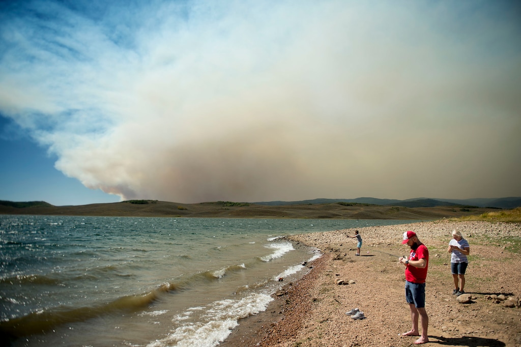 (Jeremy Harmon  |  The Salt Lake Tribune) Spencer Hall tries to fix a reel while fishing with his wife Katie and son Jonas at Strawberry Reservoir on Saturday, Sept. 15, 2018. Behind them the sky was filled with smoke from the Pole Creek Fire.