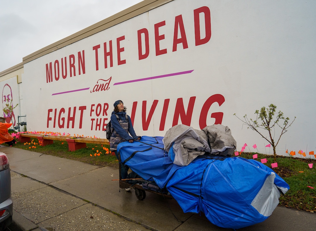 (Trent Nelson  |  The Salt Lake Tribune) A person moves their belongings as Salt Lake County conducts a camp cleanup at the Fleet Block Murals in Salt Lake City on Wednesday, April 14, 2021.