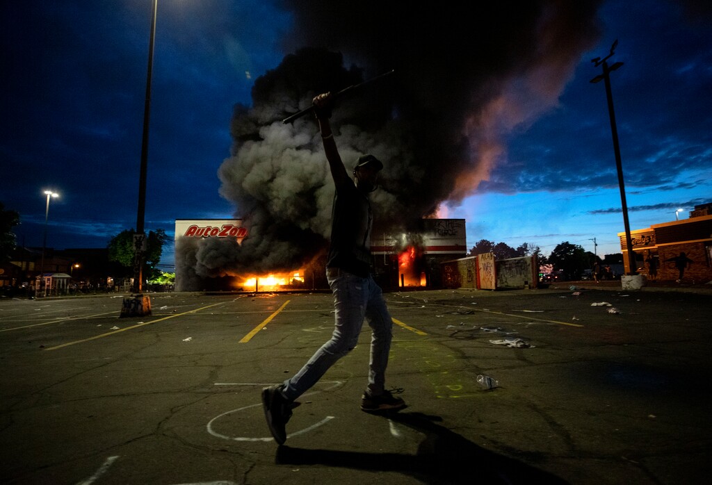 A man poses in the parking lot of an AutoZone store in flames, while protesters hold a rally against the death of George Floyd in Minneapolis on Wednesday, May 27, 2020. Violent protests over the death of the black man in police custody broke out in Minneapolis for a second straight night Wednesday, with protesters in a standoff with officers outside a police precinct and looting of nearby stores. (Carlos Gonzalez/Star Tribune via AP)