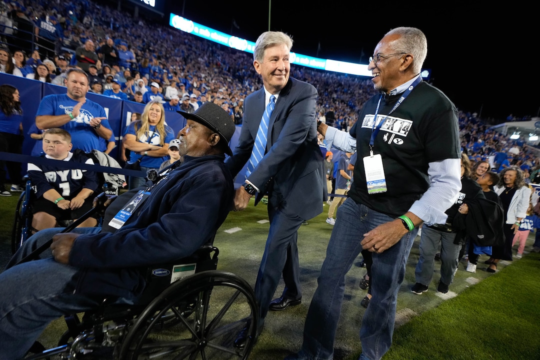 (Francisco Kjolseth | The Salt Lake Tribune) S. Gifford Nielsen General Authority Seventy of the Church of Jesus Christ of Latter-day Saints, center, pushes Mel Hamilton, left, as he talks with John Griffin, both members of the “Black 14″ — a group of Wyoming football players who were kicked off their team in 1969 for planning to protest Church of Jesus Christ of Latter-day Saints’ policies during a game against BYU. The two were being honored this week in Provo ahead of the No. 19 Cougars’ matchup with the Wyoming Cowboys, where they lit the Y on the mountain above LaVell Edwards Stadium on Saturday,  Sept. 2022. in football action between the Brigham Young Cougars and the Wyoming Cowboys at LaVell Edwards Stadium in Provo, on Saturday, Sept. 24, 2022.