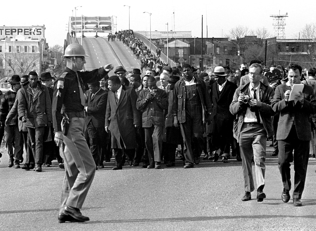(The Associated Press) In this March 10, 1965 file photo, demonstrators, including Dr. Martin Luther King, Jr., stream over an Alabama River bridge at the city limits of Selma, Ala., during a voter rights march. King's participation in the 54-mile (87-kilometer) march from Selma, Ala., to the state capital of Montgomery elevated awareness about the troubles blacks faced in registering to vote.