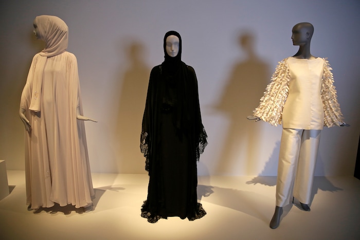 In this photo taken Thursday, Sept. 20, 2018, a black silk and lace Dolce & Gabbana ensemble, center, is displayed in the exhibit Contemporary Muslim Fashions at the M. H. de Young Memorial Museum in San Francisco. The first major museum exhibition of contemporary Muslim women's fashion reflects designs from around the world that are vibrant and elegant, playful and diverse. The show's creators hope the exhibit will show Muslim women as real people who can choose what they wear rather than as subjects ordered to cover their entire bodies or restricted in what they can wear. The exhibit opens on Saturday. (AP Photo/Eric Risberg)