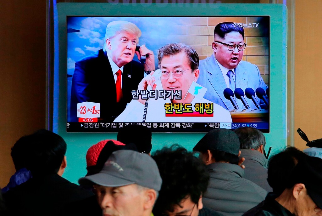 (Ahn Young-joon | The Associated Press) In this March 7, 2018, file photo, people watch a TV screen showing images of North Korean leader Kim Jong Un, right, South Korean President Moon Jae-in, center, and U.S. President Donald Trump during a news program at the Seoul Railway Station in Seoul, South Korea. The on-again, off-again meeting between President Donald Trump and North Korean leader Kim Jong Un has been an emotional roller coaster for South Koreans. With the summit now set for Tuesday, they await the historic event with both hopes and doubts. The signs read: "Thawing Korean Peninsula."