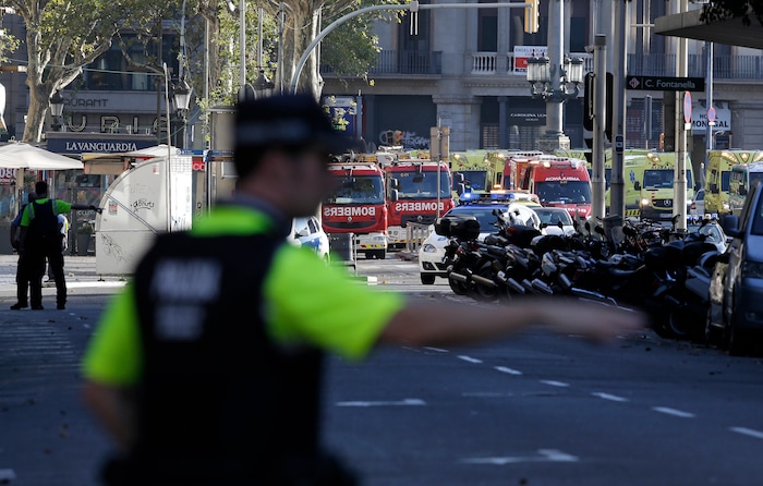 A police officer gestures as he blocks a street in Barcelona, Spain, Thursday, Aug. 17, 2017. Police in the northern Spanish city of Barcelona say a white van has jumped the sidewalk in the city's historic Las Ramblas district, injuring several people. (AP Photo/Manu Fernandez)