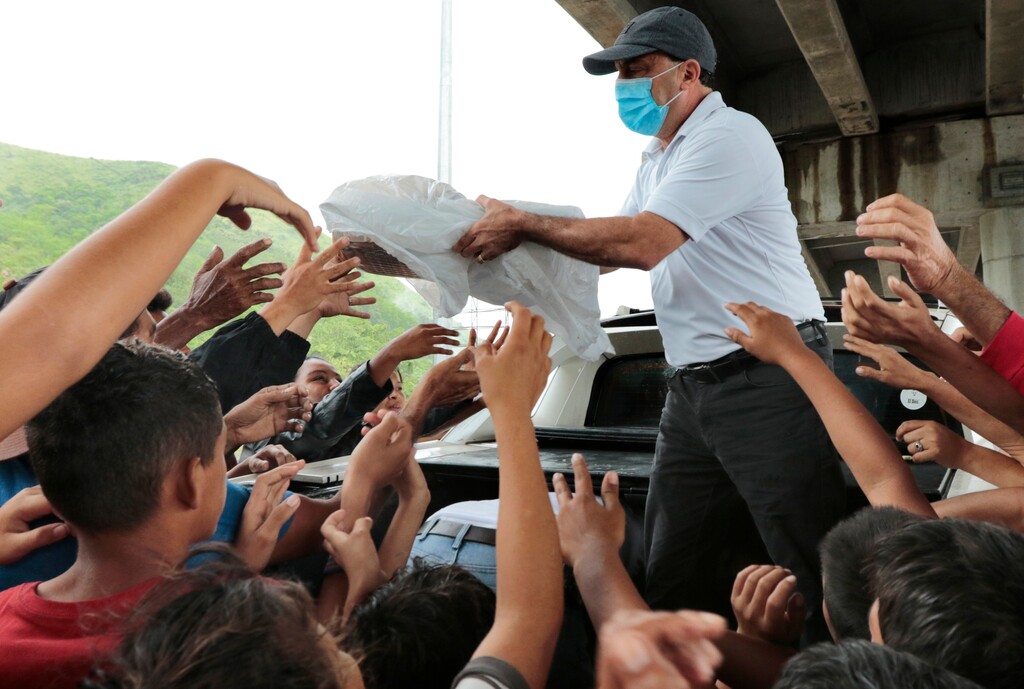 A person distributes food to hurricane victims under a bridge in San Pedro Sula, Honduras, Saturday, Nov. 21, 2020. (AP Photo/Delmer Martinez)