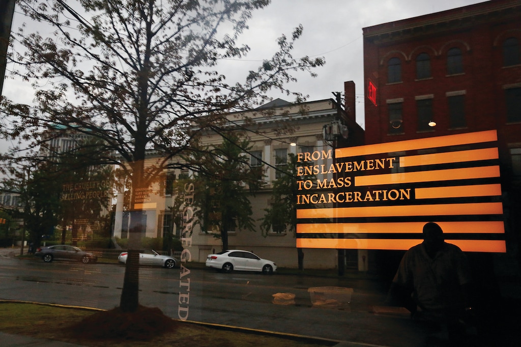 A man inside the Justice and the Legacy Museum is reflected on the front door, as an outside view is seen through the door in Montgomery, Ala., Sunday, April 22, 2018. The combined museum and a new memorial are the nation's first site to document racial inequality in America from slavery through Jim Crow to the issues of today, said the nonprofit Equal Justice Initiative, a legal advocacy group in Montgomery. (AP Photo/Brynn Anderson)