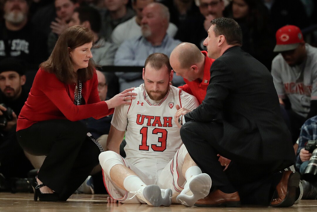 CORRECTS TO SECOND QUARTER, INSTEAD OF FIRST - Utah forward David Collette (13) is tended to by trainers after an injury during the second quarter of an NCAA college basketball game against Penn State for the NIT championship Thursday, March 29, 2018, in New York. (AP Photo/Julie Jacobson)