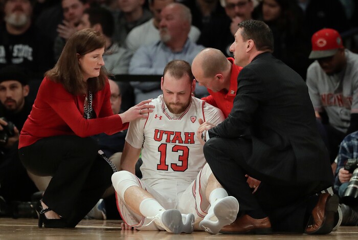 CORRECTS TO SECOND QUARTER, INSTEAD OF FIRST - Utah forward David Collette (13) is tended to by trainers after an injury during the second quarter of an NCAA college basketball game against Penn State for the NIT championship Thursday, March 29, 2018, in New York. (AP Photo/Julie Jacobson)