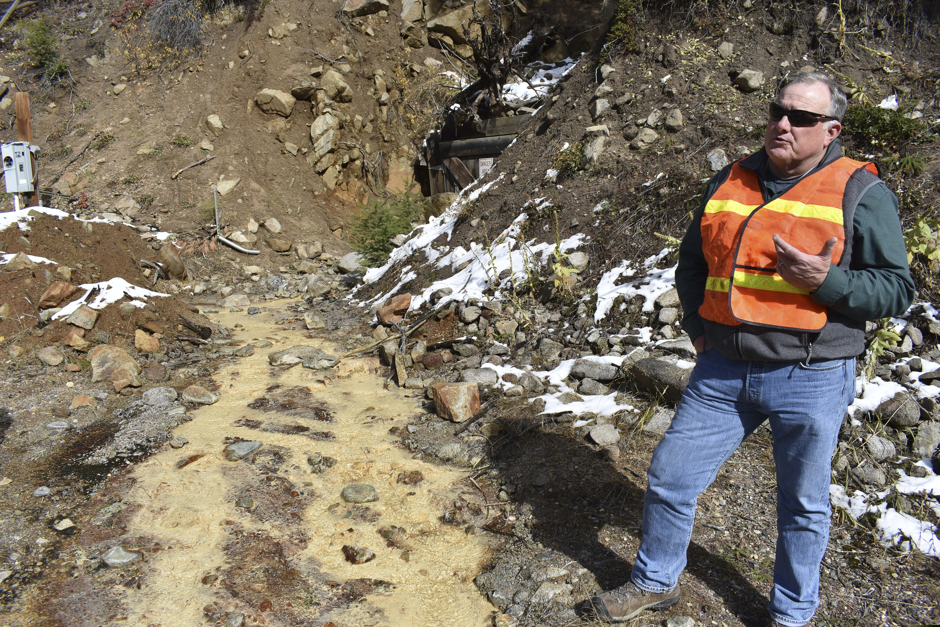 (Matthew Brown | The Associated Press) In this Oct. 12, 2018 photo, Tillman McAdams with the U.S. Environmental Protection Agency speaks about cleanup work at the Susie mine in Rimini, Mont., as polluted water from the mine flows near his feet. The mine is one of dozens that have fouled water supplies in the mountain community.