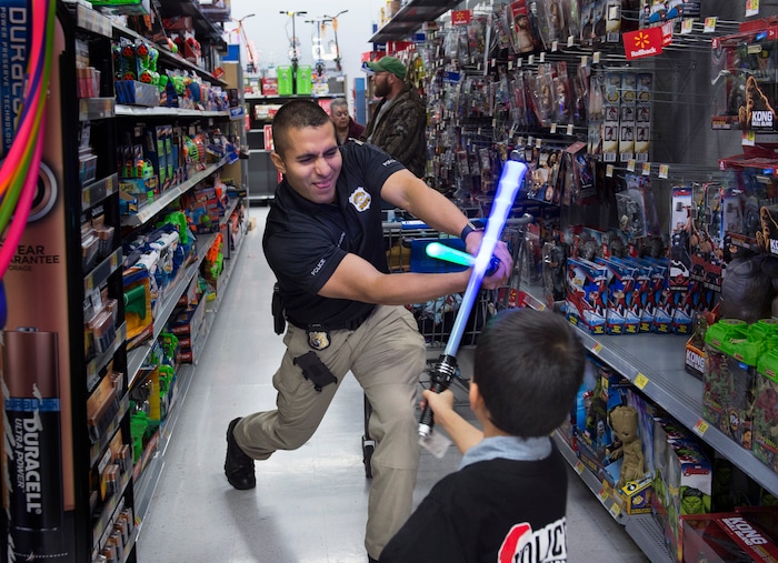 (Scott Sommerdorf   |  The Salt Lake Tribune)   Officer William Caycho tries out the light sabers with Carlos Clemente as they shop in the Walmart toy aisles at the first ever Police Pay It Forward event, Saturday, December 16, 2017.  
