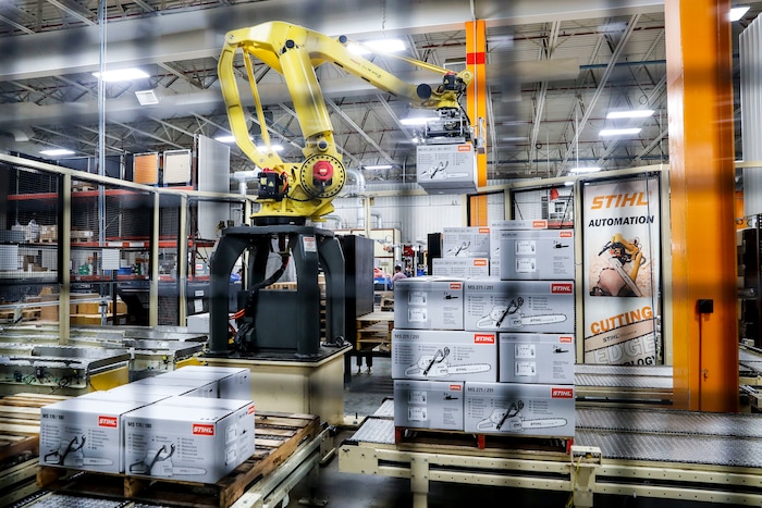 In this Thursday, May 25, 2017 photo, a giant robotic arm loads pallets full of chainsaws prepared for shipping at the Stihl Inc. production plant in Virginia Beach, Va. Despite efficiency increases and lessening the need for manual laborers, companies require workers who can program, oversee, operate, and maintain the automation. A report by Deloitte Consulting and the American Manufacturing Institute estimates 2 million such jobs will need to be filled over the next decade. (AP Photo/John Minchillo)