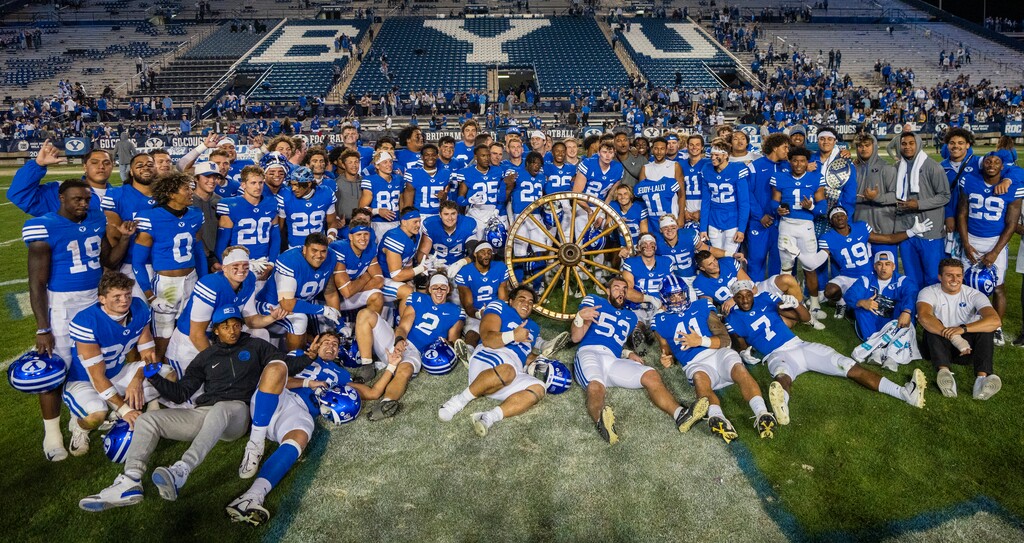 (Rick Egan | The Salt Lake Tribune) The Brigham Young Brigham Young Cougars pose for a photo with the Wagon Wheel, after they defeated the Utah State Aggies 38-26, at LaVell Edwards Stadium in Provo, on Thursday, Sept. 29, 2022.