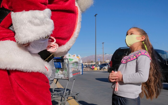 (Leah Hogsten  |  The Salt Lake Tribune)  Lyla Miller, 6, asks Santa Claus for a pair of skis in her stocking at MaceyÕs grocery store on Thursday, to which her father Chris Miller replied, "Well, this is the first I've heard of that." The jolly fat man also greeted Macey's guests who scheduled a grocery pickup time, Dec. 24, 2020.