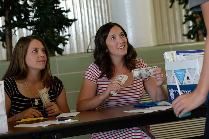 (Francisco Kjolseth  |  The Salt Lake Tribune)  Administrative interns Amy Sandgren, left, and Sara Allen engage with incoming high school freshman students on how their day went before handing over $5 for their daily participation in summer school. Students who participate in the Husky Strong summer school program receive the money to get a head start on the school year.