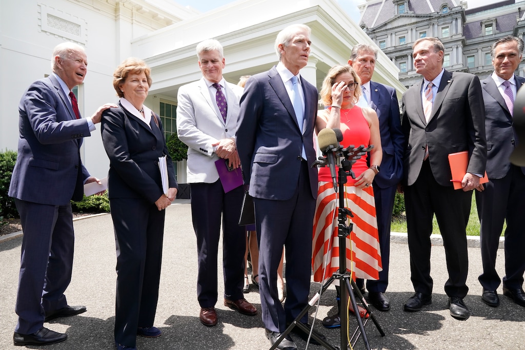 (Jacquelyn Martin | AP) President Joe Biden walks off after speaking to the media, as from left, Sen. Jeanne Shaheen, D-N.H., Sen. Bill Cassidy, R-La., Sen. Rob Portman, R-Ohio, Sen. Kyrsten Sinema, D-Ariz, Sen, Joe Manchin, D-W.Va., Sen. Mark Warner, D-Va., and Sen. Mitt Romney, R-Utah, look on, Thursday June 24, 2021, at the White House in Washington. Biden invited members of the group of 21 Republican and Democratic senators to discuss the infrastructure plan.