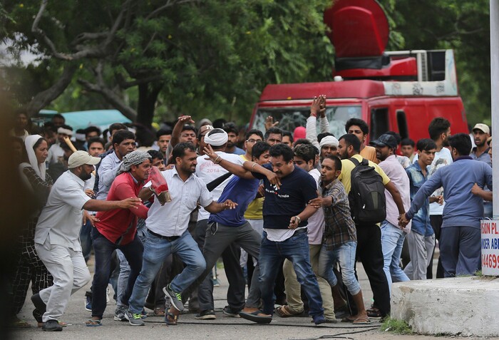 Supporters of the Dera Sacha Sauda sect attack a member of the media, foreground wearing a blue dark t-shirt, in Panchkula, India, Friday, Aug. 25, 2017. Police used water cannon in an attempt to disperse the crowd. More than 15,000 paramilitary troops and police officers, some on horseback, were deployed in the town of Panchkula. (AP Photo/Altaf Qadri)