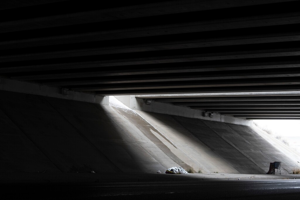 (Rick Egan | The Salt Lake Tribune)  Trying to to find shelter from the snow, Rachel Ramos covers herself with a blanket under an overpass, because Salt Lake City is not allowing unsheltered people to sleep in tents, on Tuesday, December 28, 2021.