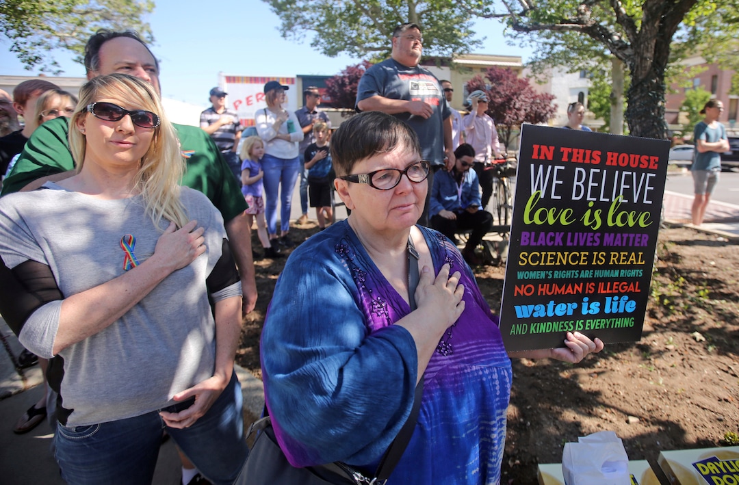 Martha Hales, right, holds a sign during a news conference to discuss the America's Freedom Festival's decision Thursday, June 14, 2018, in Provo, Utah. LGBT groups that were denied requests to participate in a July 4 parade that is part of America's Freedom Festival in Provo spoke out Thursday about being rejected even after festival organizer and Provo city officials signed a nondiscrimination deal. (AP Photo/Rick Bowmer)