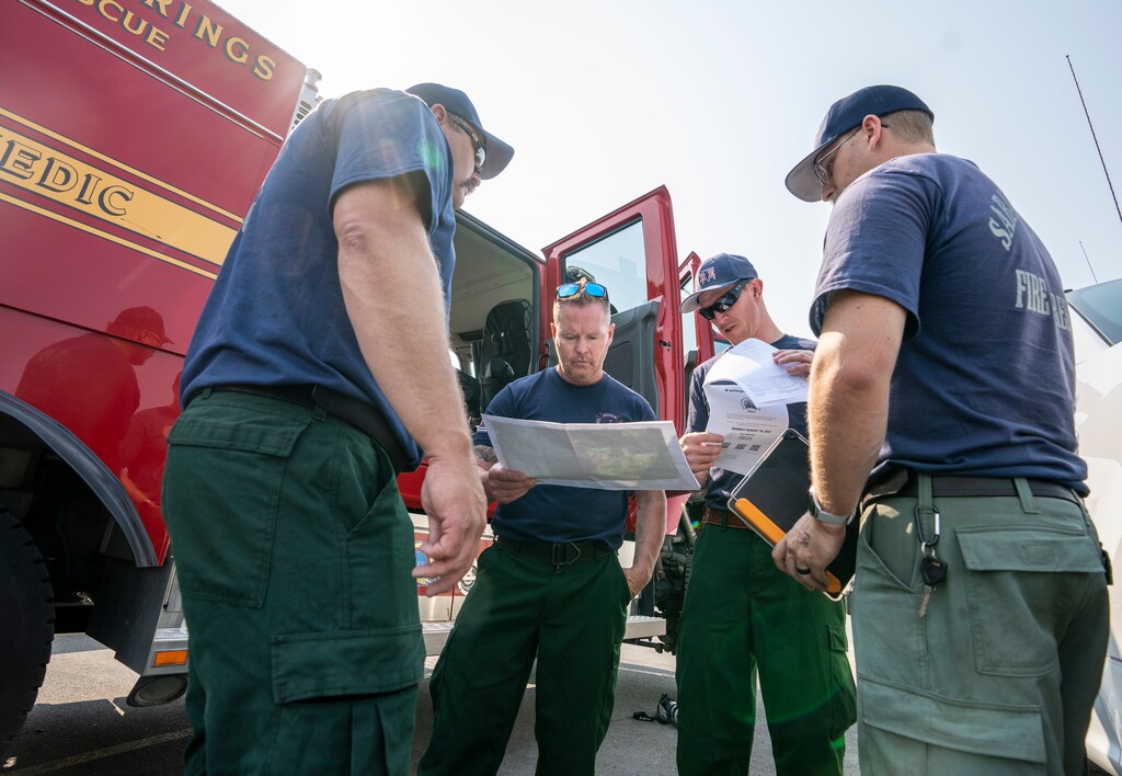 (Leah Hogsten | The Salt Lake Tribune Firefighter/EMT Taylor Olsen, second from right, and fellow members of the Saratoga Springs Fire Deparment review a map of where the team will head to on the Parleys Canyon Fire as it continues to threaten at least 6,000 houses, Aug. 16, 2021.