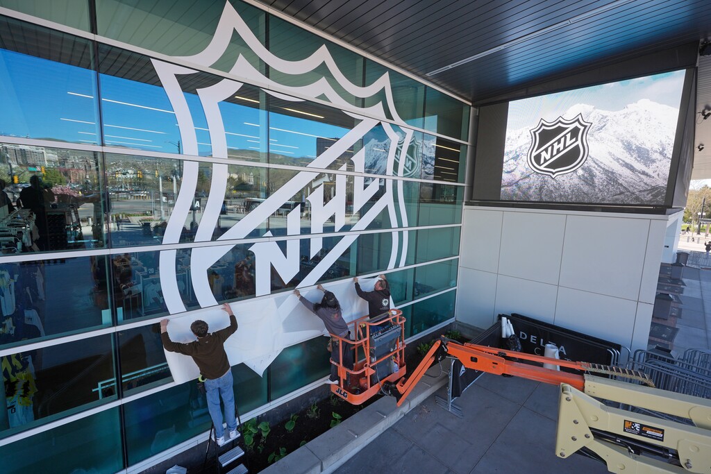 (Rick Bowmer | AP) Workers put up signs celebrating the sale of the Arizona Coyotes and its accompanying relocation to Salt Lake City, at the Delta Center on Thursday, April 18, 2024, in Salt Lake City. The NHL team will be known as Utah, at least initially. New owner Ryan Smith says the name will begin with Utah and he does not want to rush the process of rebranding the franchise upon relocation.