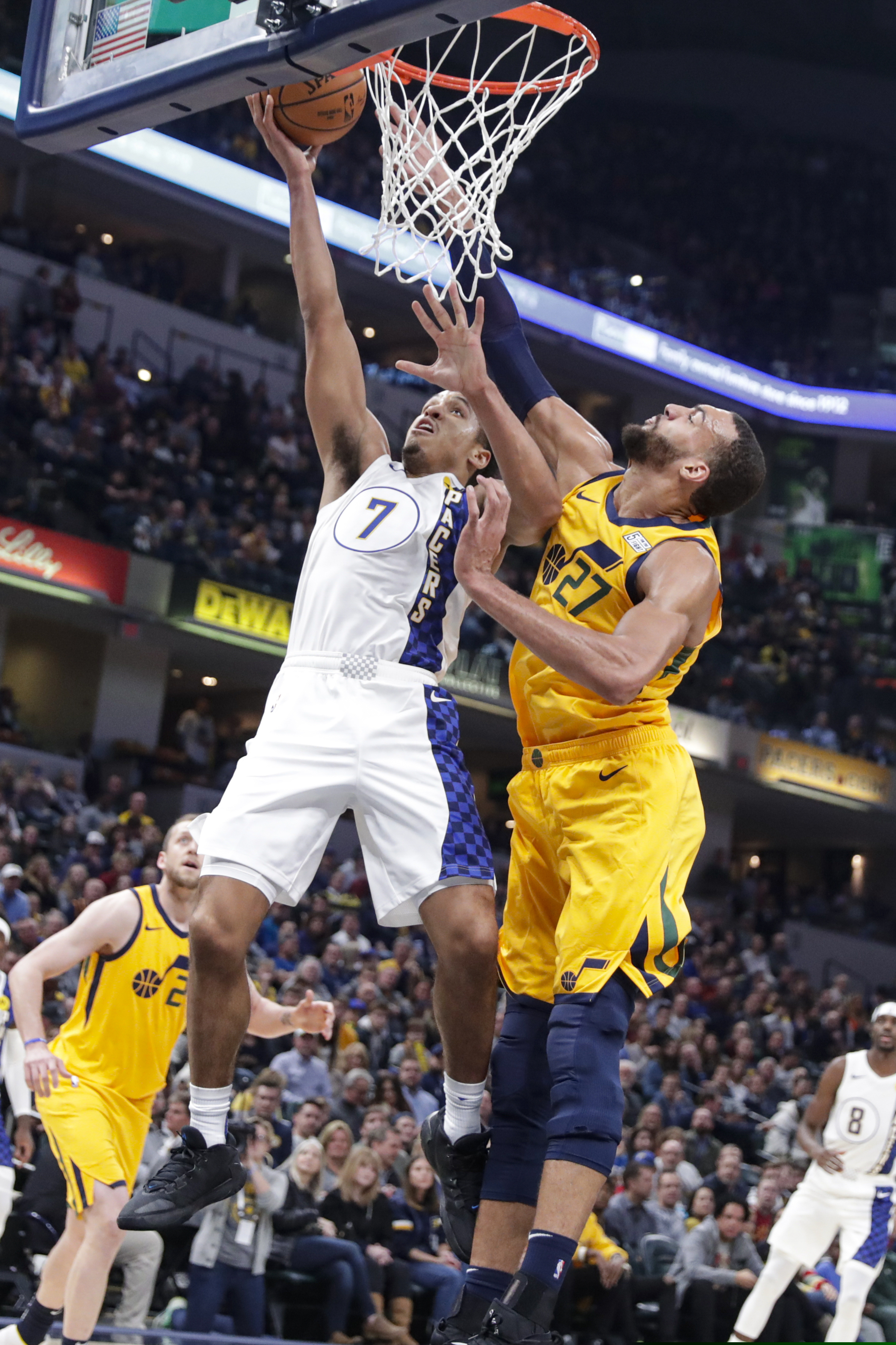 Indiana Pacers guard Malcolm Brogdon (7) is fouled by Utah Jazz center Rudy Gobert (27) during the first half of an NBA basketball game in Indianapolis, Wednesday, Nov. 27, 2019. (AP Photo/Michael Conroy)
