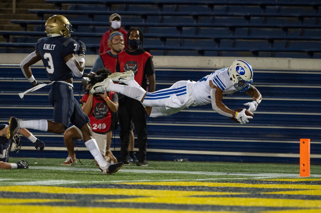 (Tommy Gilligan | AP) BYU running back Tyler Allgeier, right, dives for a touchdown as Navy cornerback Cameron Kinley (3) looks on during the first half of an NCAA college football game, Monday, Sept. 7, 2020, in Annapolis, Md.