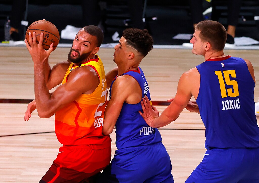 Utah Jazz's Rudy Gobert, left, is defended by Denver Nuggets' Michael Porter Jr., center, and Nikola Jokic (15) during the third quarter of an NBA basketball game Saturday, Aug. 8, 2020, in Lake Buena Vista, Fla. (Kevin C. Cox/Pool Photo via AP)