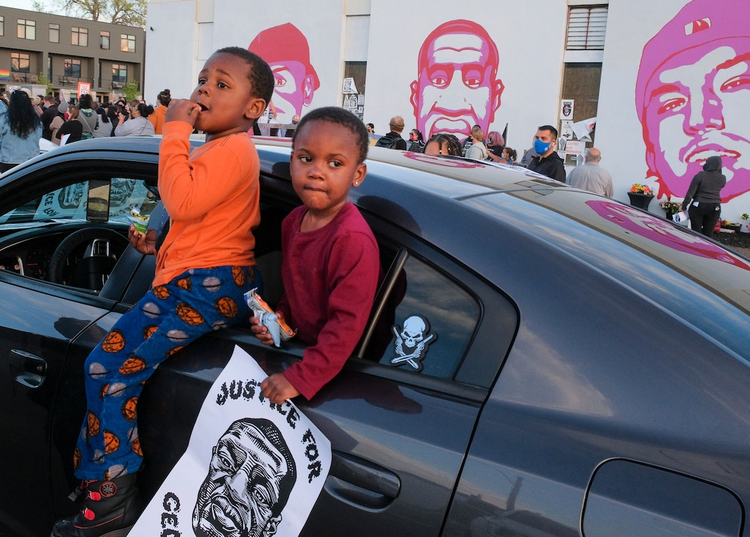 (Leah Hogsten | The Salt Lake Tribune)  Brothers Jamari and J.C. Butoyi hang out of the family car waving "Justice for George Floyd" signs as they celebrate with their mother Nyree Hicks at George Floyd's mural in downtown Salt Lake City on Tuesday, April 20, 2021, following the guilty verdict on all three counts in the murder trial of former Minneapolis police Officer Derek Chauvin in the death of George Floyd.