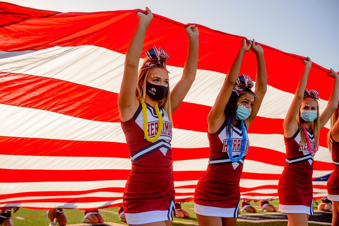 (Trent Nelson  |  The Salt Lake Tribune) Herriman cheerleaders hold a flag during the National Anthem while hosting Davis High School football, in Herriman on Thursday, Aug. 13, 2020.