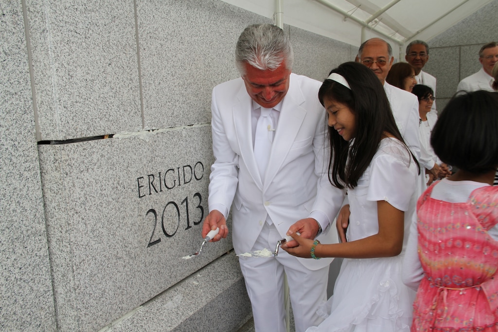 (The Church of Jesus Christ of Latter-day Saints)
Apostle Dieter F. Uchtdorf helps a young Latter-day Saint girl place mortar securing the cornerstone of the Tegucigalpa Honduras Temple in March 2013.