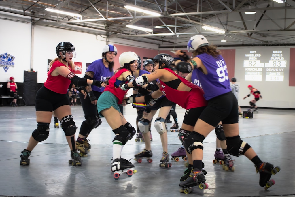(Frank Regalado  |  Amplify Utah) Hannah Rivas, in the green shorts, who skates under the derby name Menstrual Psycho, breaks position as a jammer, at right with the purple star on their helmet, slips by during a Wasatch Roller Derby match. Rivas said the league is run by and based on the community, and “without
that community, it would just completely fall apart.”