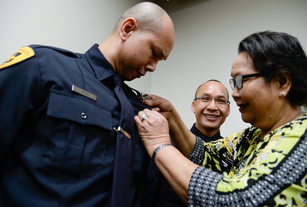 (Francisco Kjolseth  |  The Salt Lake Tribune)  Salt Lake City Airport Police officer Ry Kros is pinned with a new badge by his mother Rem Dorado as his brother Ran Kros, also an airport police officer jokes around, during a ceremony to retire their former patch and badge as they are subsumed into the Salt Lake City Police Department on Tuesday, Feb. 26, 2019. 