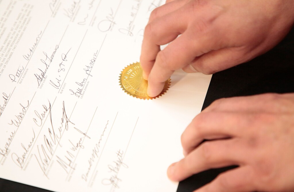 (Joshua A. Bickel | The Columbus Dispatch via AP)
An Ohio Secretary of State staff member places an official seal on the Certificate of Votes certifying Ohio's 18 electoral votes for President Donald J. Trump during the 55th Electoral College on Monday, Dec. 14, 2020 at the Ohio Statehouse in Columbus, Ohio. Ohio's 18 electors cast their votes for President of the United States.