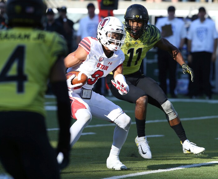 Utah's Darren Carrington II, center, runs between Oregon cornerback Thomas Graham Jr., left, and Oregon linebacker Justin Hollins after a reception during the first quarter of an NCAA college football game Saturday, Oct. 28, 2017, in Eugene, Ore. (AP Photo/Chris Pietsch)