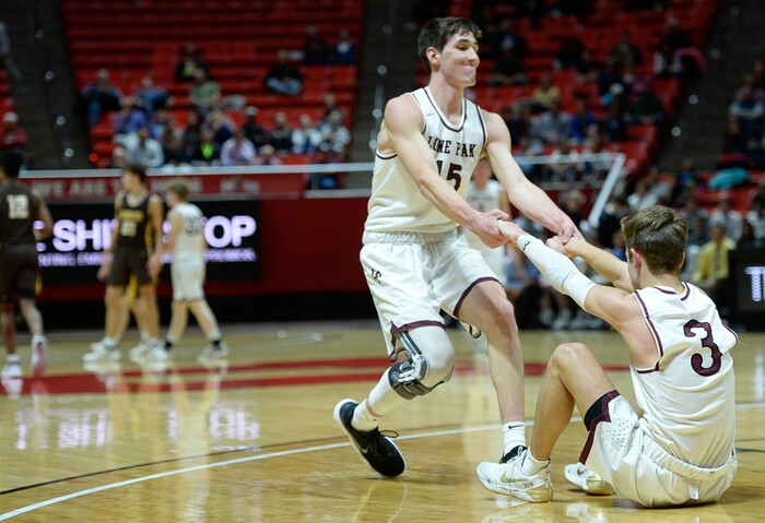 (Francisco Kjolseth  |  The Salt Lake Tribune)  Davis vs Lone Peak, 6A State high school basketball tournament at the Huntsman Center in Salt Lake City, Thursday March 1, 2018. Jaxon Pollard (15) helps up teammate Steven Ashoworth (3). 