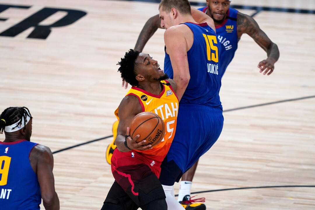 Utah Jazz's Donovan Mitchell, center, is fouled by Denver Nuggets' Nikola Jokic (15) during the second half of an NBA basketball first round playoff game Sunday, Aug. 30, 2020, in Lake Buena Vista, Fla. (AP Photo/Ashley Landis)