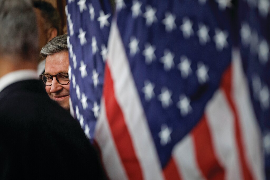House Speaker Mike Johnson, R-La., peers through American flags during a news conference on the SAVE America Act on Capitol Hill in Washington, Wednesday, Feb. 11, 2026, in Washington. (AP Photo/Tom Brenner)
