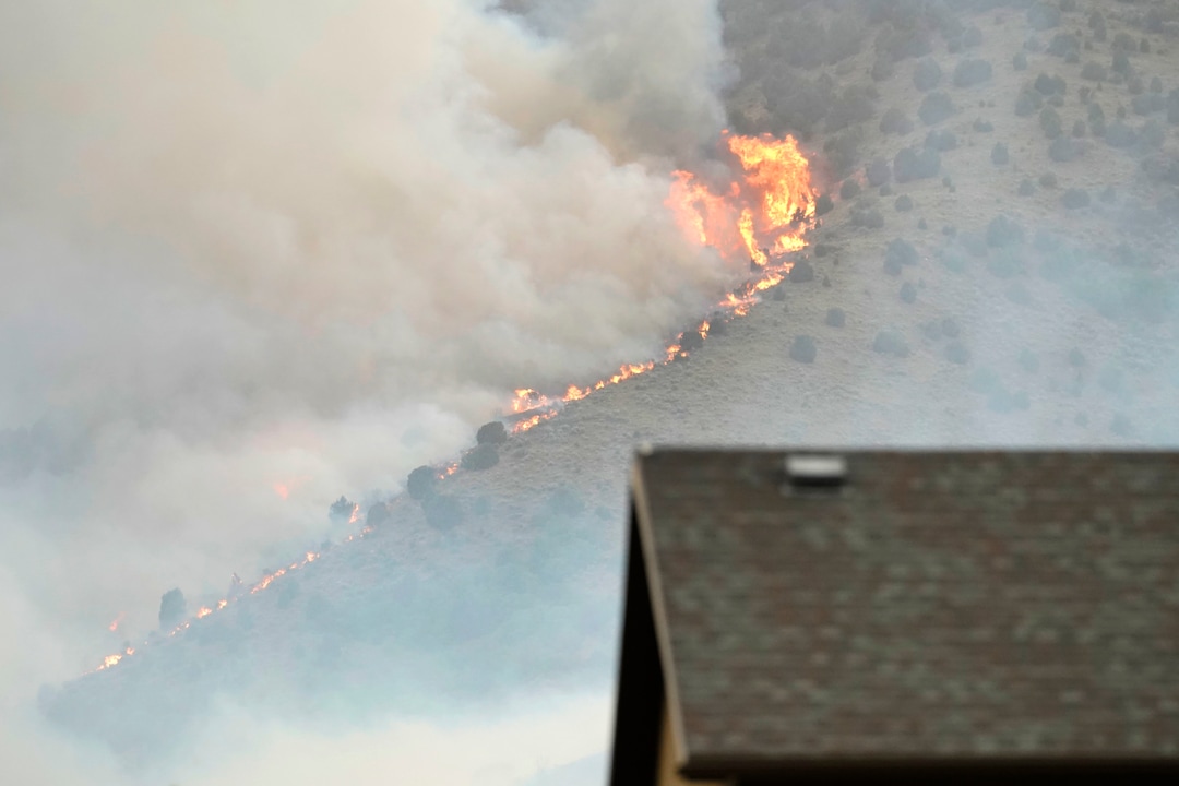 (George Frey | Special to The Tribune) Flames from a wildfire rise above homes in south Saratoga Springs on June 28, 2020.