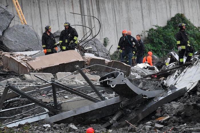 Rescues work among the rubble of the collapsed Morandi highway bridge in Genoa, northern Italy, Tuesday, Aug. 14, 2018. A large section of the bridge collapsed over an industrial area in the Italian city of Genova during a sudden and violent storm, leaving vehicles crushed in rubble below. (Luca Zennaro/ANSA via AP)