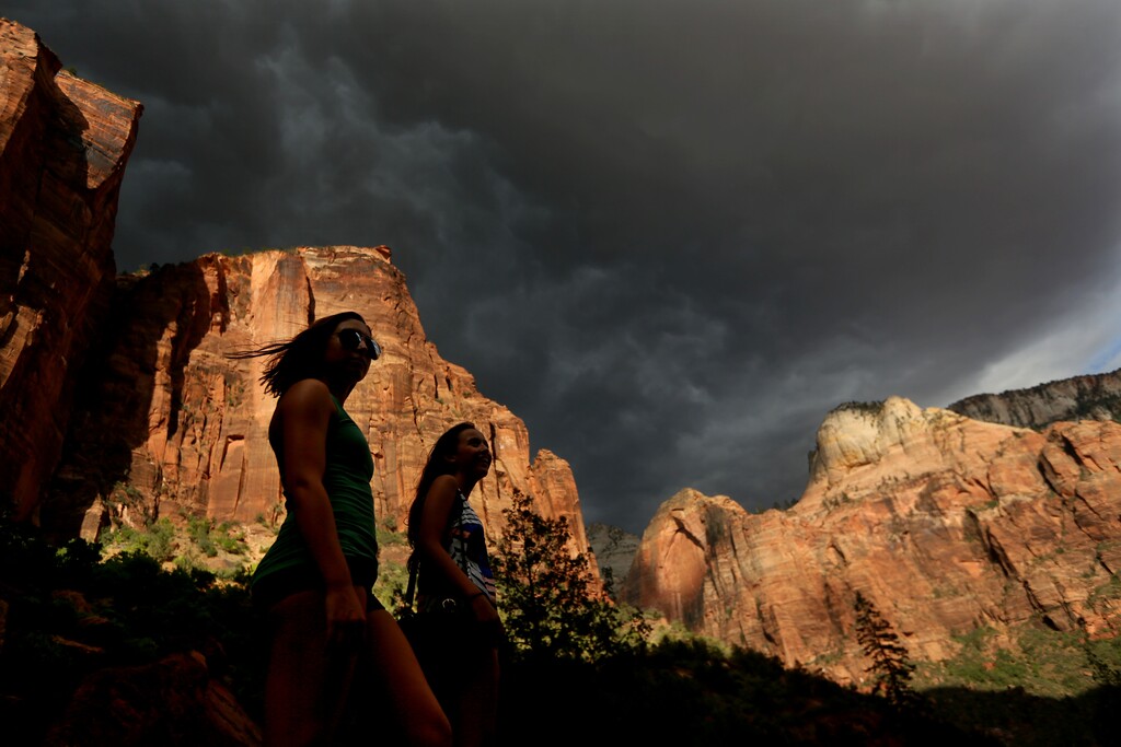 (AP file photo) Hikers look up at a fast moving storm as it makes its way through Zion National Park outside of Springdale, as seen in 2015. Utah Gov. Gary Herbert is urging the Interior Department to reconsider a proposal for raising entrance fees at many of the nation’s marquee national parks, saying it could hurt park visitation,  Utah’s tourism industry and rural businesses.