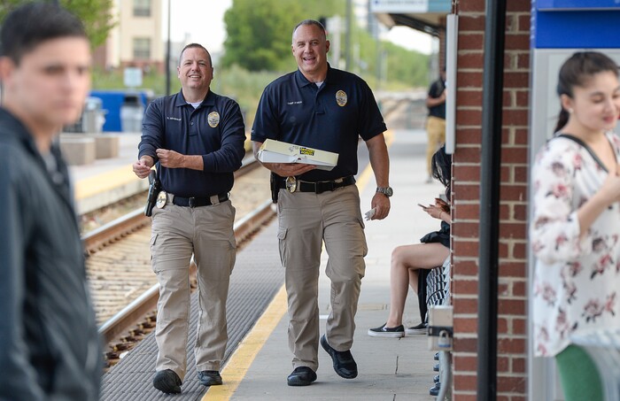 (Francisco Kjolseth | The Salt Lake Tribune) Sandy Police Captain Greg Severson, left, and interim Chief Bill O'Neal visit the Sandy Civic Center TRAX Station in honor of National Donut Day to team up with Sandy Mayor Kurt Bradburn to hand out donuts to morning commuters on Friday, June 1, 2018.