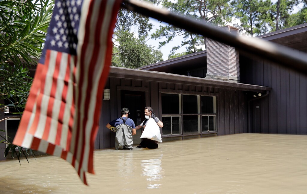 Gaston Kirby, right, and Juan Minutella leave Kirby's flooded home in the aftermath of Hurricane Harvey, Monday, Sept. 4, 2017, near the Addicks and Barker Reservoirs, in Houston. (AP Photo/David J. Phillip)